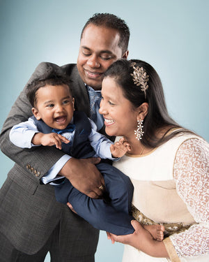Family of three posing together against a light blue background