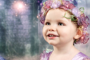 Child wearing a colorful fairy costume with a blurred fairy-tale background