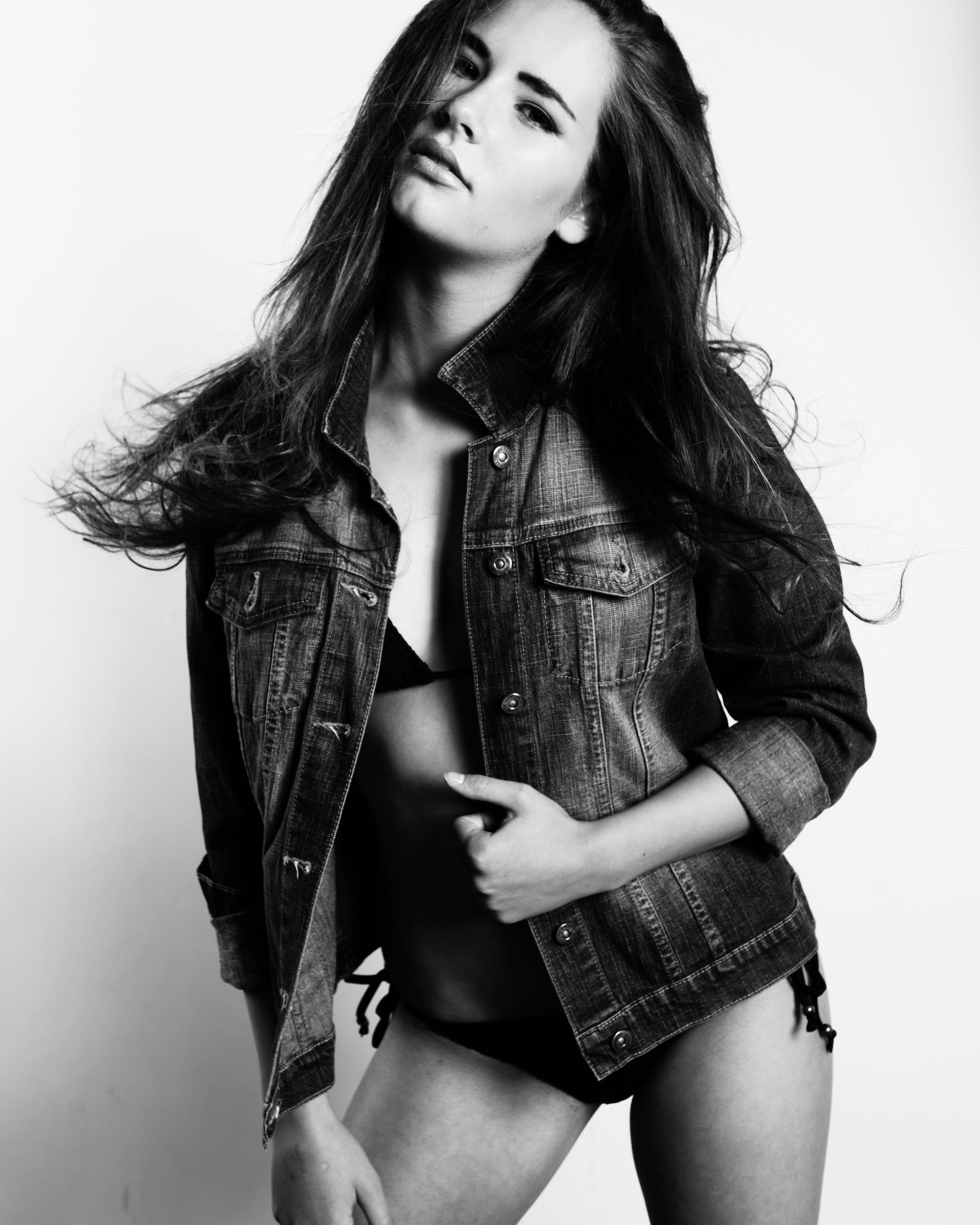 Black and white photo of a person wearing a denim jacket over lingerie.