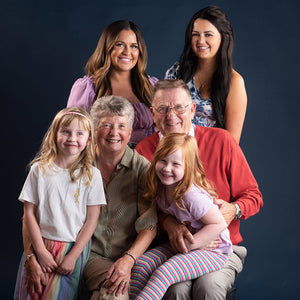 Family portrait with three generations of people against a dark background