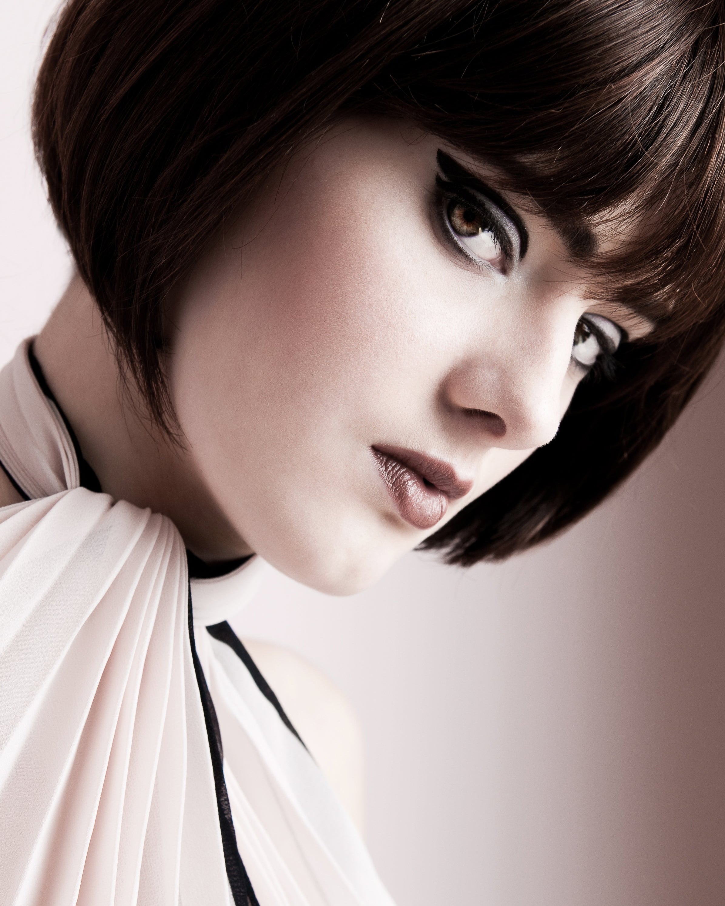 Close-up of a model Bibba style imspired with short hair wearing a light-colored garment against a neutral background